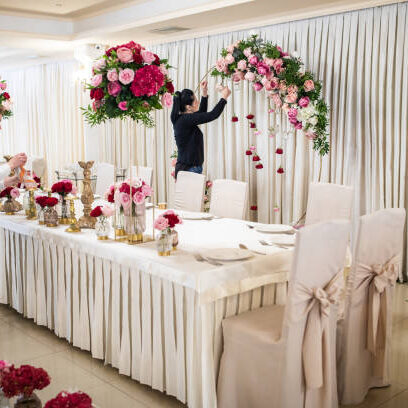 Two hard working women finishing decorating of banquet hall with blossom flowers