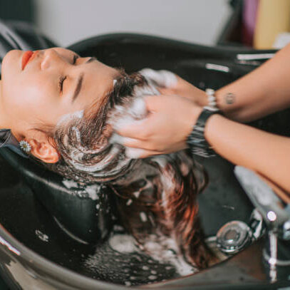 Directly above Asian chinese female lying down for hair wash at hair salon with eyes closed